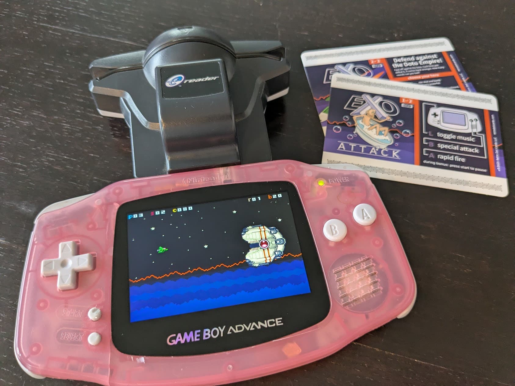 A Game Boy Advance playing Exo Attack with a USA E-Reader and English cards nearby